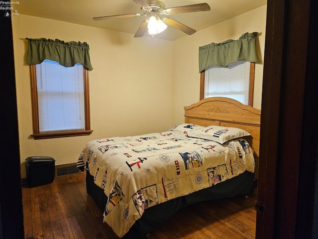 bedroom with a ceiling fan, dark wood-style floors, and visible vents