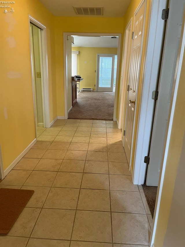 hallway featuring light tile patterned floors, baseboards, visible vents, a baseboard radiator, and light carpet