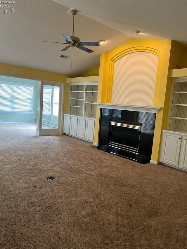 unfurnished living room featuring vaulted ceiling, a fireplace with flush hearth, a ceiling fan, and carpet floors