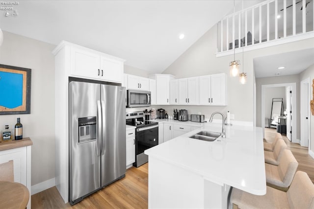 kitchen featuring a breakfast bar area, a peninsula, light wood-style flooring, a sink, and appliances with stainless steel finishes