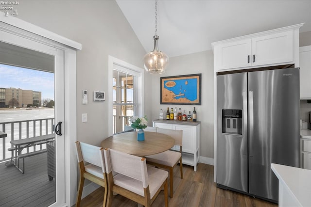 dining room featuring baseboards, a chandelier, dark wood-style flooring, and vaulted ceiling