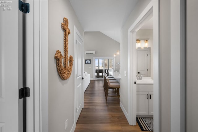 corridor with a sink, baseboards, lofted ceiling, and dark wood finished floors