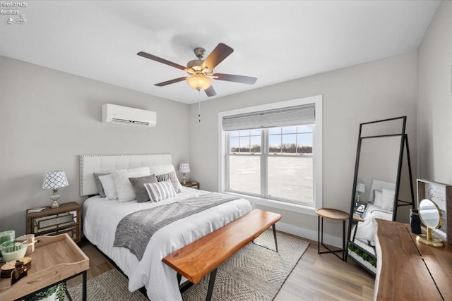 bedroom featuring baseboards, wood finished floors, a ceiling fan, and a wall mounted AC