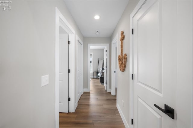 corridor featuring recessed lighting, dark wood-type flooring, and baseboards