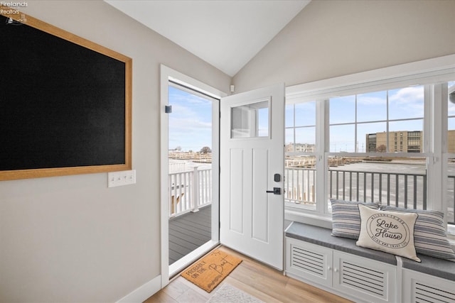 doorway to outside with light wood-style flooring, baseboards, and lofted ceiling