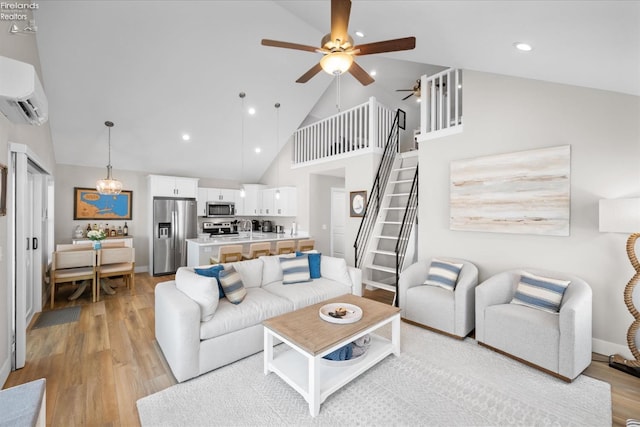 living area featuring an AC wall unit, light wood-style flooring, recessed lighting, ceiling fan, and stairs