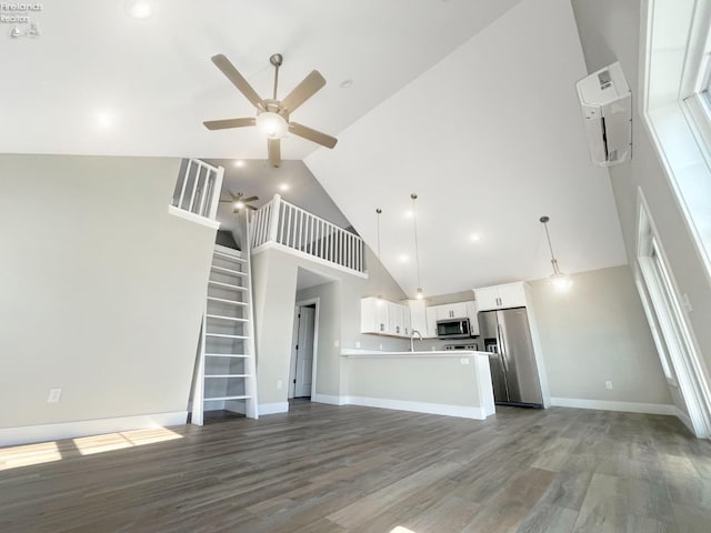 unfurnished living room with a sink, wood finished floors, stairway, baseboards, and ceiling fan