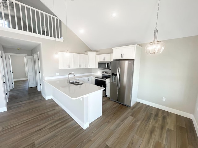 kitchen featuring dark wood-style floors, a peninsula, a sink, stainless steel appliances, and light countertops