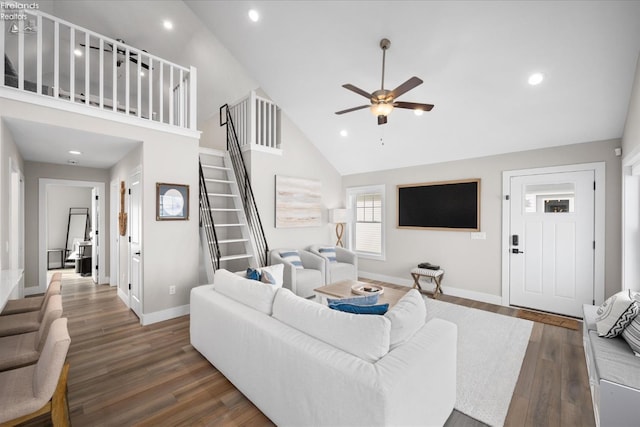 living area with stairway, baseboards, dark wood-type flooring, and high vaulted ceiling