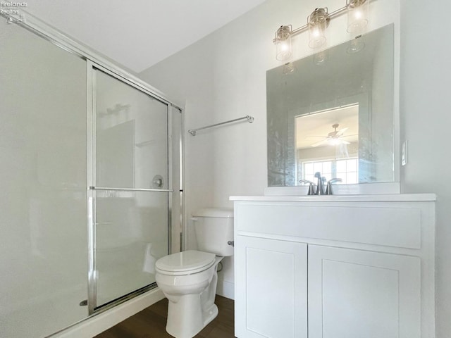 bathroom with wood finished floors, toilet, a stall shower, and vanity