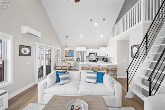 living area featuring a wall mounted air conditioner, stairs, baseboards, and wood finished floors