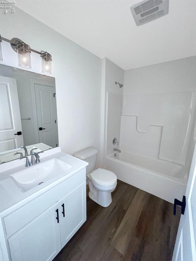 bathroom with vanity, wood finished floors, visible vents, tub / shower combination, and toilet