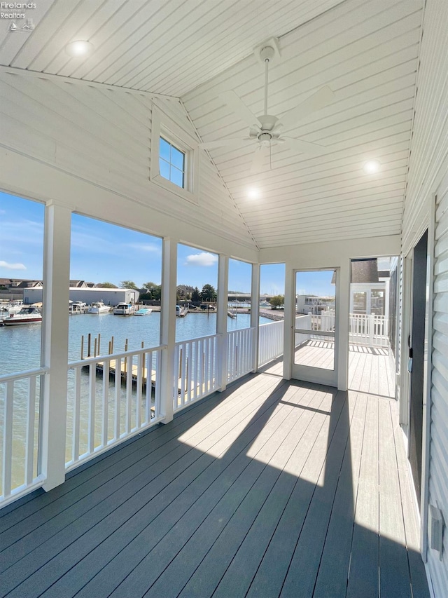 unfurnished sunroom featuring lofted ceiling, ceiling fan, and a water view