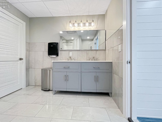 full bathroom featuring double vanity, tile walls, and a sink