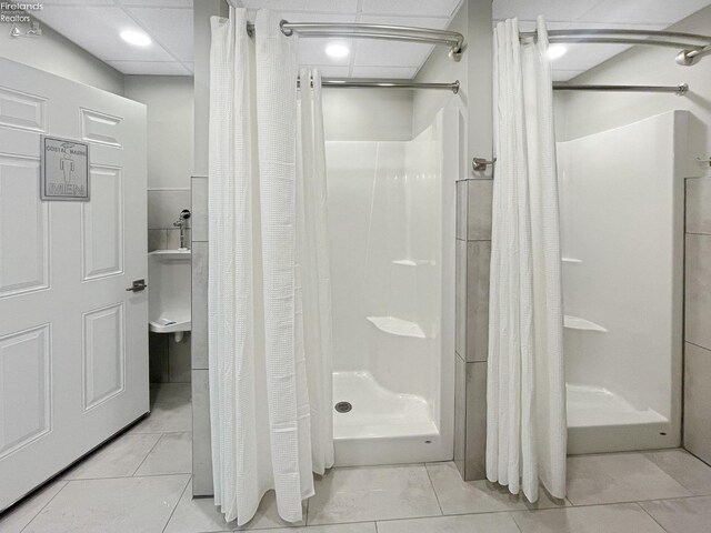 full bathroom with tile patterned floors, a drop ceiling, and a shower stall