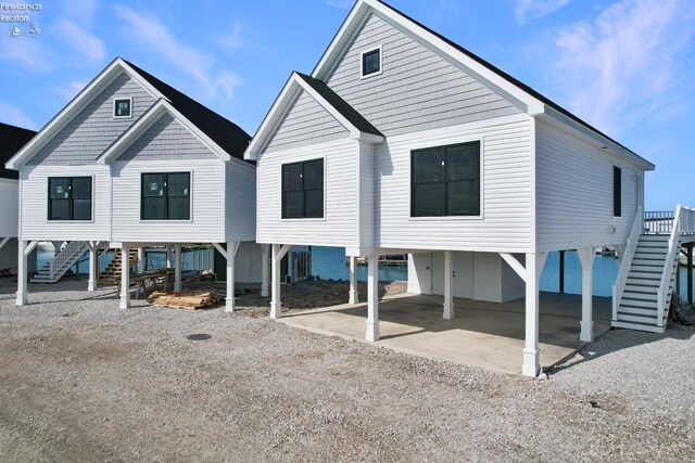 back of property with stairs, a carport, driveway, and a patio