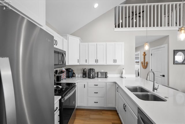 kitchen featuring light wood finished floors, light countertops, white cabinets, stainless steel appliances, and a sink