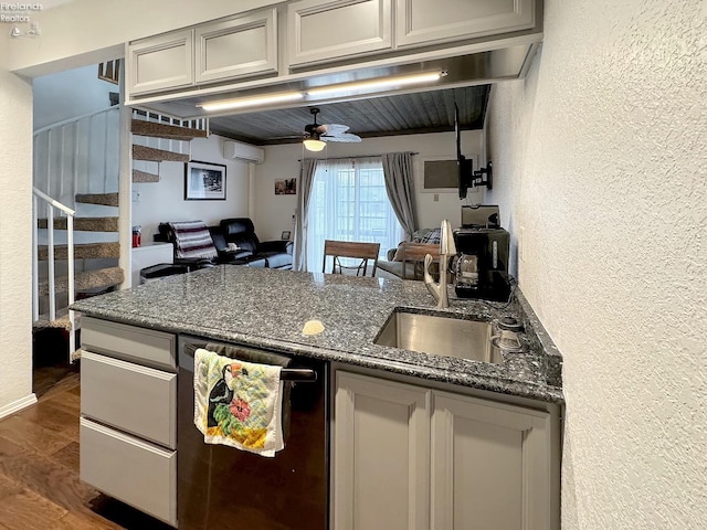 kitchen featuring dishwashing machine, a sink, dark wood-type flooring, a wall mounted air conditioner, and a textured wall