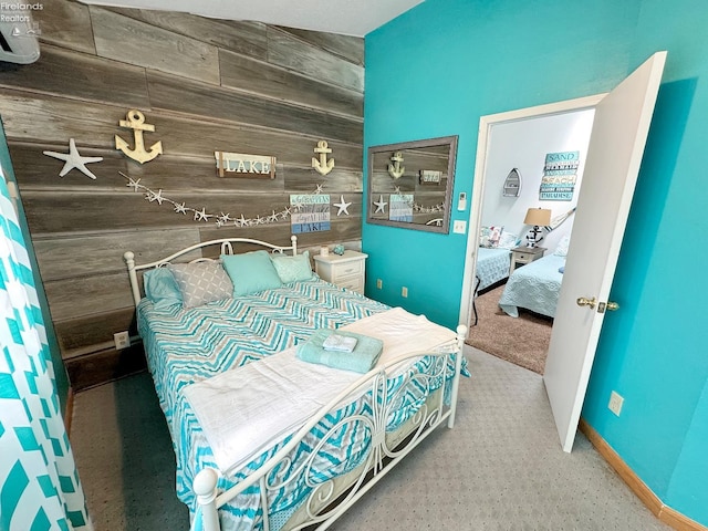 carpeted bedroom featuring wood walls and an accent wall