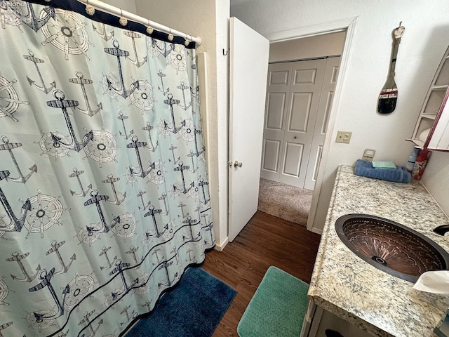 bathroom with vanity, a shower with shower curtain, a textured wall, and wood finished floors