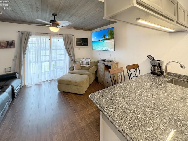 living room with a ceiling fan, dark wood-type flooring, and wood ceiling