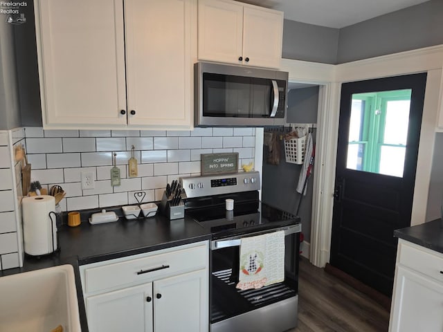 kitchen featuring dark countertops, appliances with stainless steel finishes, and white cabinets