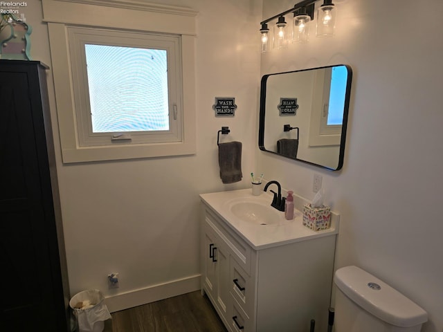 bathroom featuring toilet, vanity, baseboards, and wood finished floors