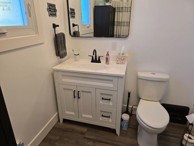 bathroom with vanity, toilet, wood finished floors, and baseboards