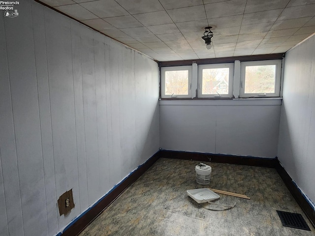 empty room featuring a wealth of natural light, visible vents, and baseboards