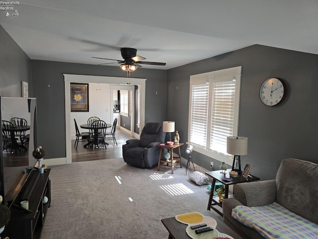 carpeted living room with a ceiling fan and baseboards