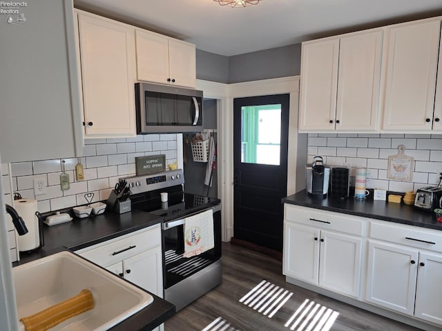 kitchen with stainless steel appliances, dark wood-type flooring, dark countertops, and white cabinetry