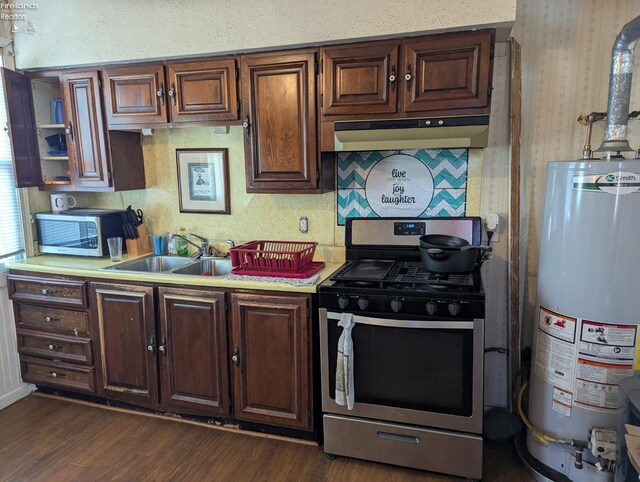 kitchen featuring under cabinet range hood, gas water heater, stainless steel appliances, light countertops, and dark wood-style flooring