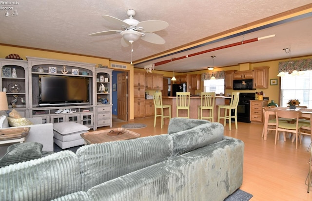 living area featuring visible vents, light wood-style floors, ceiling fan, and ornamental molding