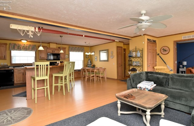 living room featuring light wood-type flooring, visible vents, a textured ceiling, and ceiling fan with notable chandelier