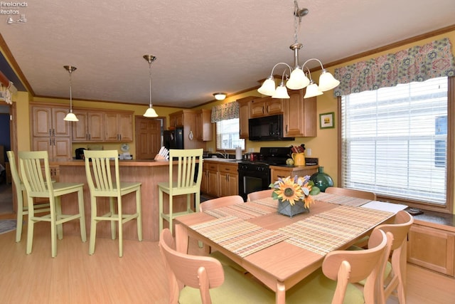 dining space with an inviting chandelier, crown molding, light wood finished floors, and a textured ceiling