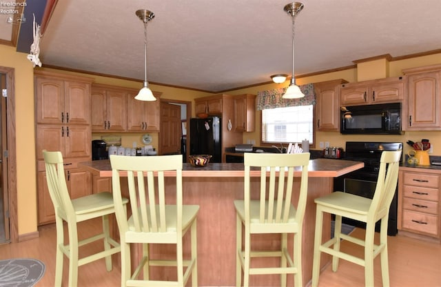 kitchen with light wood-type flooring, black appliances, a kitchen breakfast bar, crown molding, and hanging light fixtures