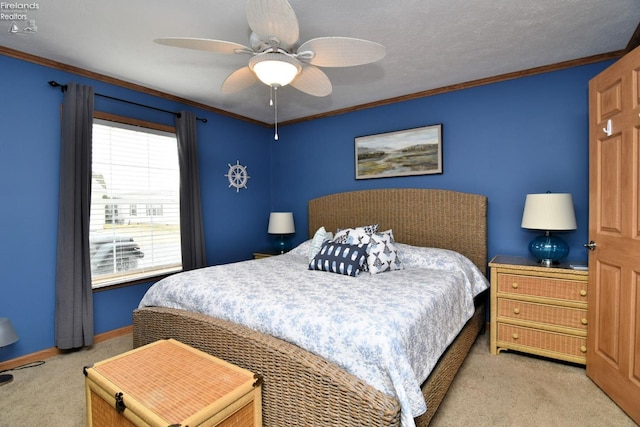 carpeted bedroom with baseboards, ornamental molding, and a ceiling fan