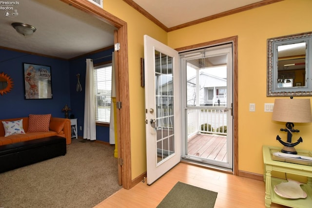 doorway to outside featuring baseboards, crown molding, and light wood-style floors