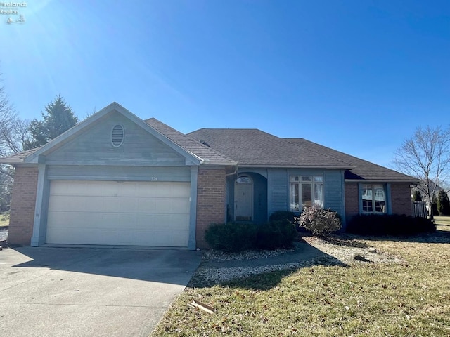 single story home with a shingled roof, concrete driveway, a front lawn, a garage, and brick siding