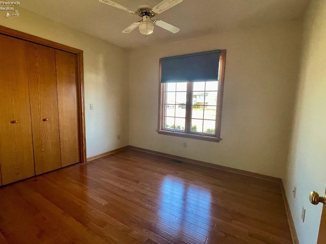 unfurnished bedroom with a closet, ceiling fan, baseboards, and hardwood / wood-style flooring