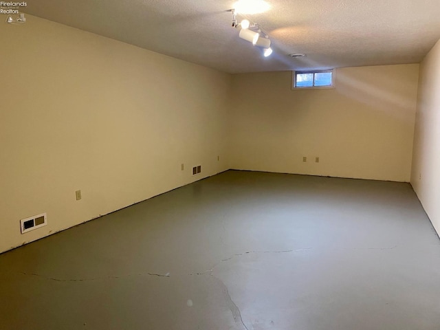 interior space with finished concrete floors, a textured ceiling, and visible vents