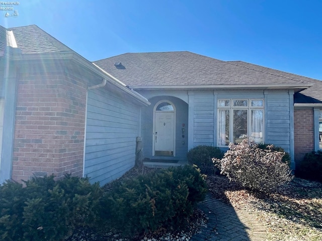 property entrance with brick siding and roof with shingles