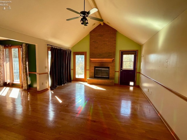 unfurnished living room with beamed ceiling, a ceiling fan, hardwood / wood-style flooring, baseboards, and a brick fireplace