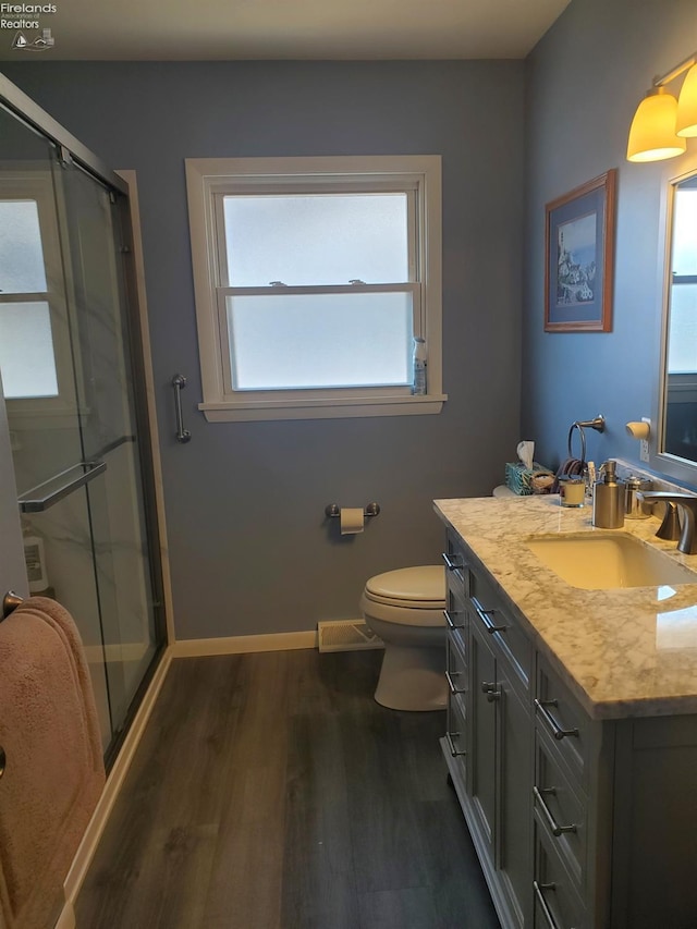 bathroom featuring baseboards, toilet, wood finished floors, and a shower stall