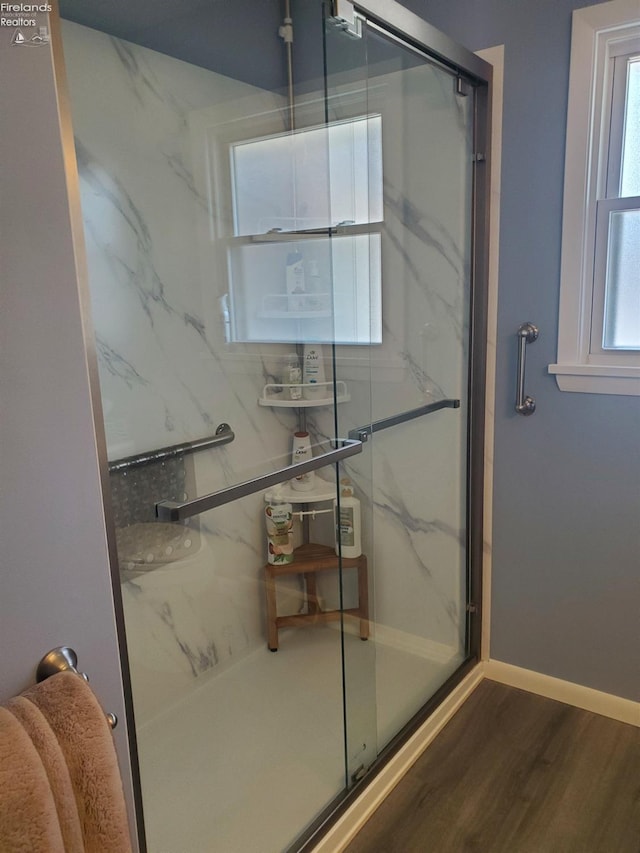 full bathroom featuring a marble finish shower, baseboards, and wood finished floors