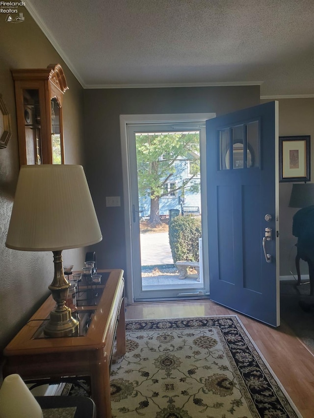 foyer with ornamental molding, wood finished floors, and a textured ceiling