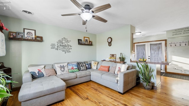 living room featuring visible vents, baseboards, a ceiling fan, and wood finished floors