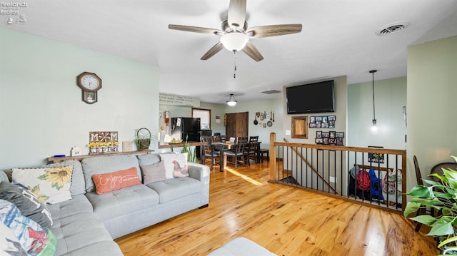 living room featuring visible vents, ceiling fan, and wood finished floors