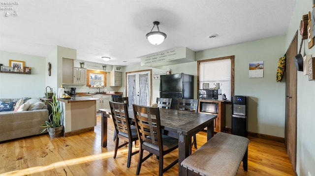 dining room with baseboards, light wood-type flooring, plenty of natural light, and visible vents