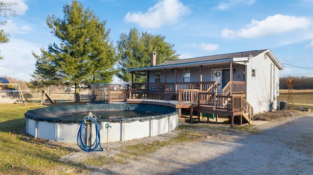 rear view of house with a covered pool, central air condition unit, a lawn, and covered porch